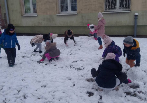 Dzieci toczą kule na śniegu